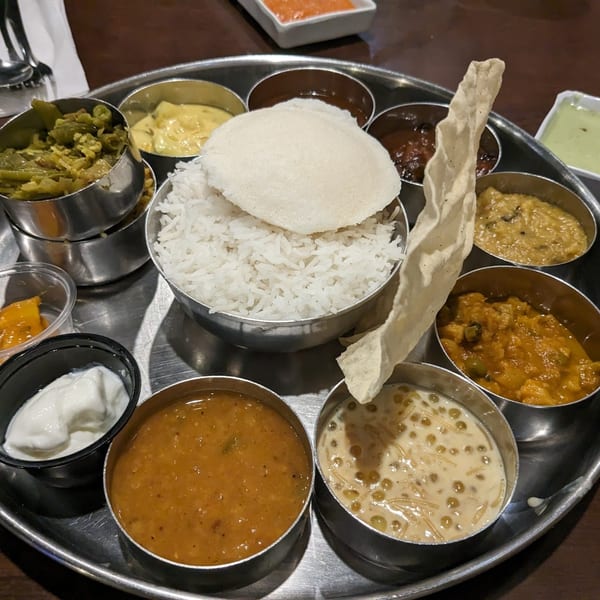 A Chennai Dosa Hut thali with rice, idli, papadum, and various Indian curries and desserts.