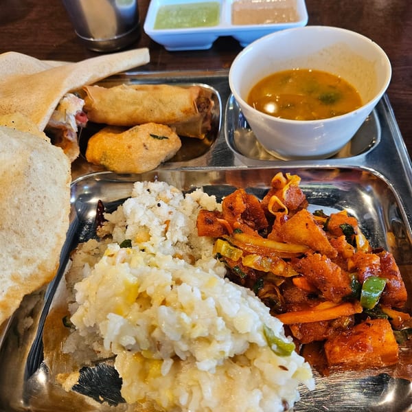 A Chennai Dosa Hut Indian thali with dosa, spring rolls, vada, sambar, rice, and chili paneer.